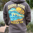Load image into Gallery viewer, Person wearing a hoodie with 'Shore Born Supply Co.' design on the back outdoors.